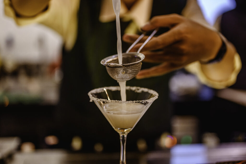 close up of cocktail being poured into martini glass