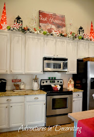 white kitchen cabinets with green garland and lots of decorations 