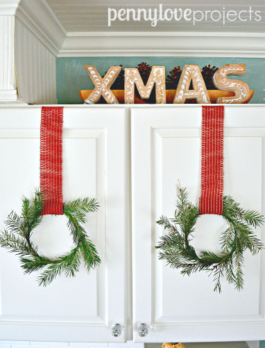 white cabinets with Christmas sign and 2 wreaths