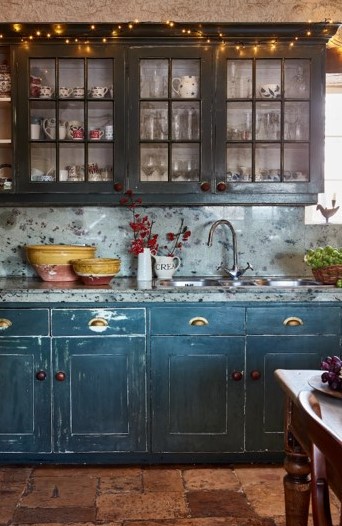 Dark blue kitchen cabinets with one strand of lights across the top 