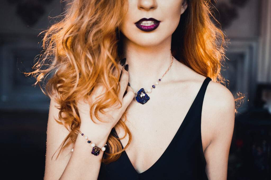 Woman with red hair, black lipstick and jewelry. Close up. 