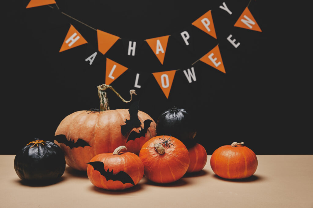 Orange pumpkins with black paper bats and Halloween banner on a black background