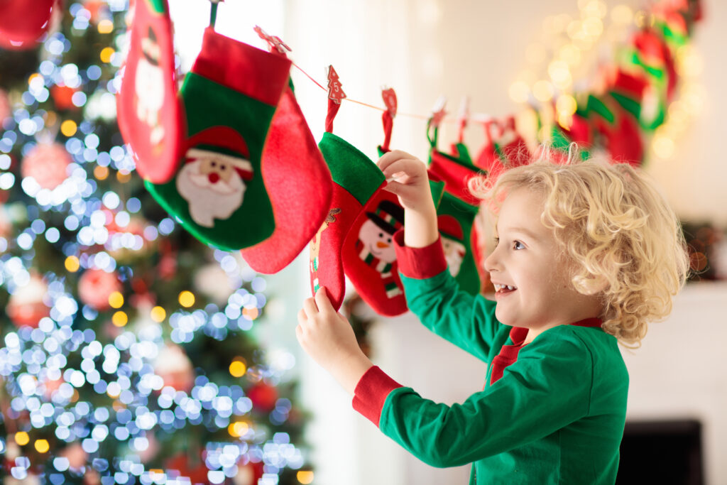 Young boy in pajamas by a Christmas tree with small stocking advent calendar