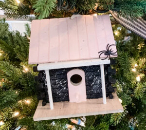 small pink birdhouse with black spider